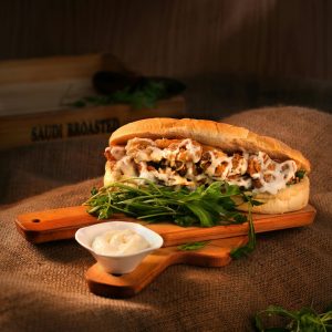 Delicious chicken sandwich with mayonnaise and greens served on a wooden board.